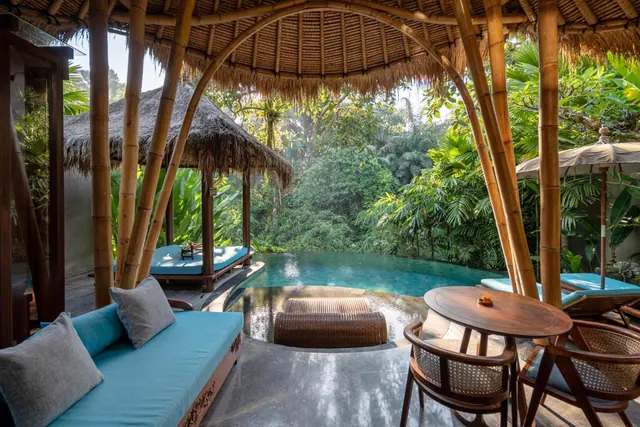 A covered terrace with a small plunge pool, a daybed, sun loungers and a round wooden table overlooks dense jungle vegetation.