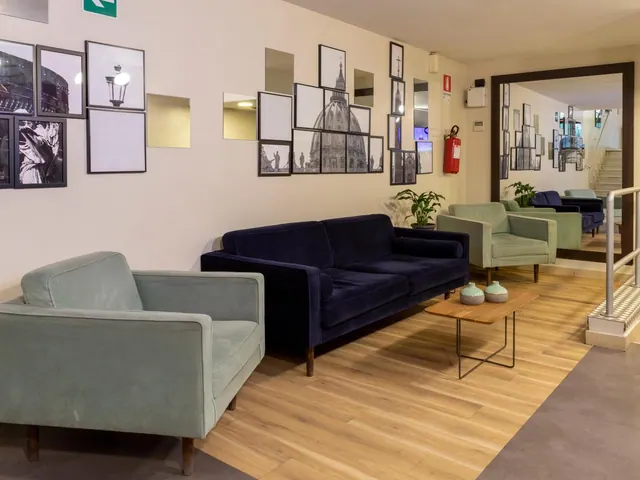 A lounge seating area with a navy sofa, green armchairs, a wooden coffee table, and framed black and white prints on the wall.