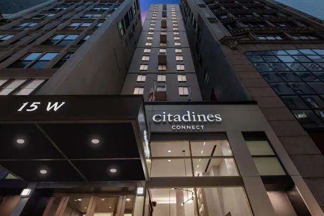 Low-angle dusk view of a tall hotel building with the Citadines Connect sign and the 15 W address sign at street level.