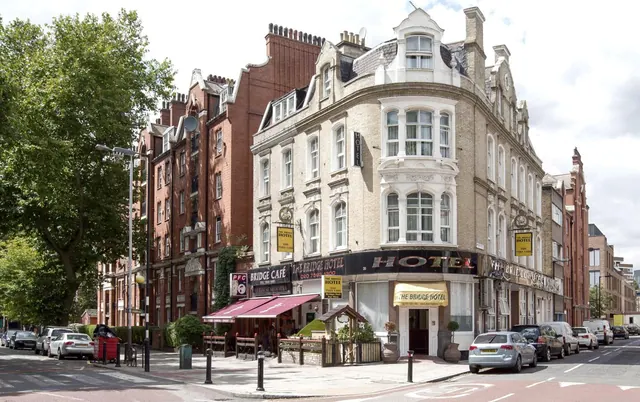 Exterior of a cream and red brick corner building with The Bridge Hotel and Bridge Café signage, with parked cars along the street.
