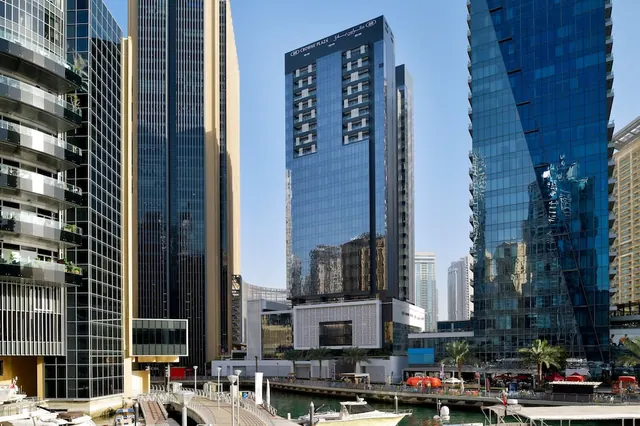 Glass high-rise towers line a marina waterfront with moored boats, and the Crowne Plaza tower stands in the centre of the frame.