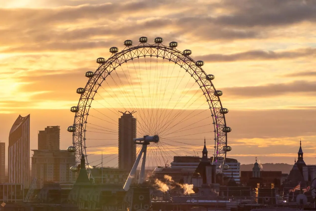 The London Eye and a city skyline are seen at sunset, with steam rising from buildings in the foreground.