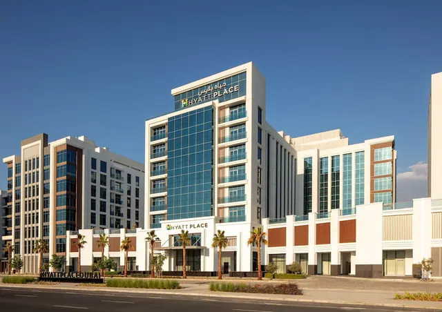 Exterior of a multi-storey Hyatt Place hotel building with palm trees along the street under a clear blue sky.