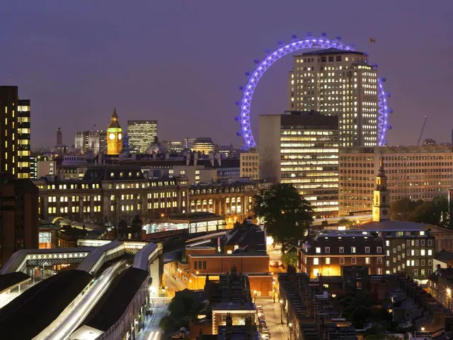 A dusk view over London's skyline with the illuminated London Eye, a lit clock tower and rail station buildings in the foreground.