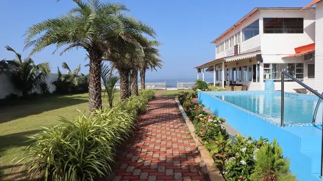 A small pool beside a landscaped garden and brick path overlooks the sea.