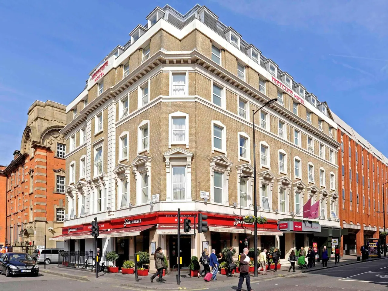 Exterior of a corner Mercure hotel building with a Faberunkels restaurant at street level, with pedestrians and parked cars on the street.