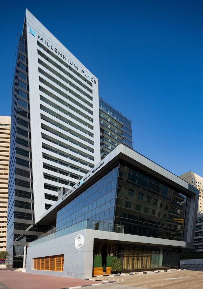 Exterior view of the Millennium Place hotel tower and glass-fronted entrance building under a clear blue sky.