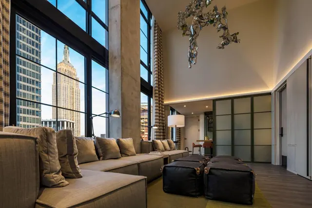 A living area with a large sectional sofa, floor-to-ceiling windows, and a view of the Empire State Building.