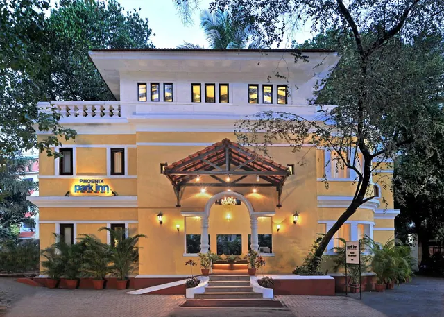 The hotel entrance is shown with a covered portico, illuminated windows, steps, and potted plants.
