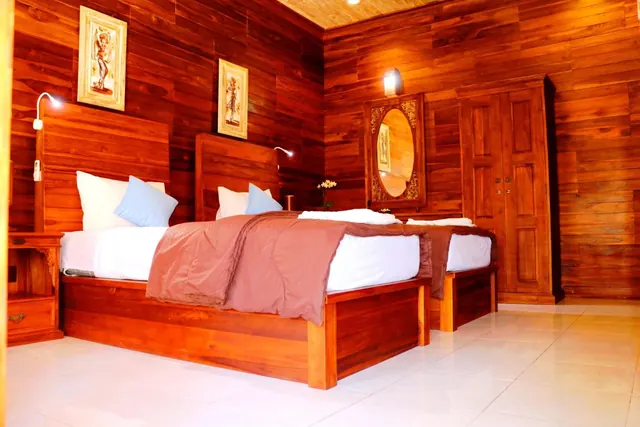 A wood-panelled bedroom with a double bed, a second bed at right, a carved wooden wardrobe and a round mirror on the wall.