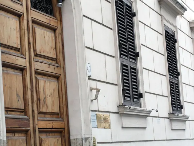 A large wooden street door and a white plastered facade with dark shutters, house number 40, and small plaques beside the entrance.