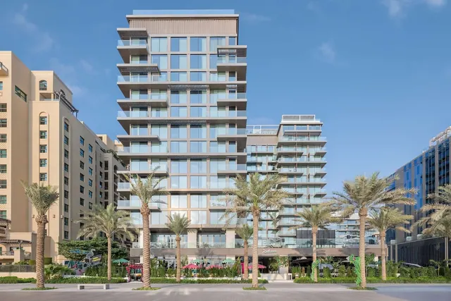 Exterior of a tall tower with stacked balconies and glass facade, with palm trees in front and a Radisson sign at street level under a clear blue sky.