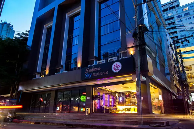 Exterior of the Sakura Sky Residence building at dusk, with its illuminated ground-floor lobby and sign facing the street.