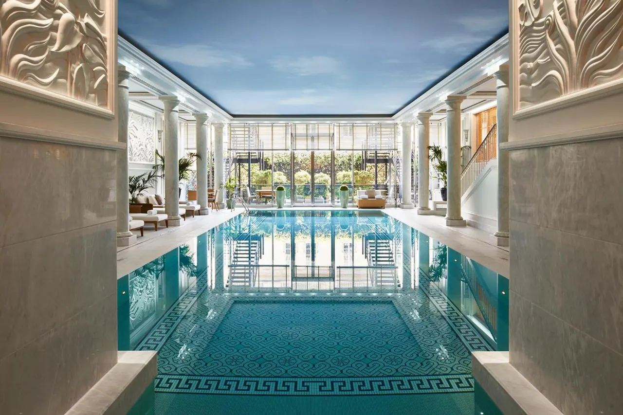 A large indoor pool occupies a bright, column-lined room with ornate decorative details and garden-facing windows.