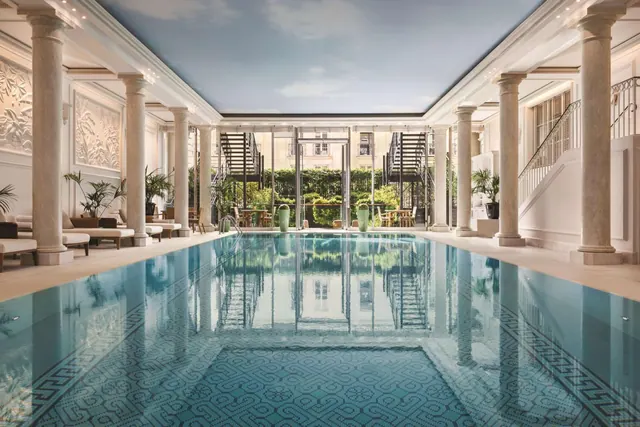 A large indoor pool is framed by columns and overlooks a planted courtyard.