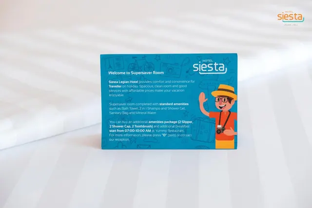 A printed welcome card for the Supersaver Room stands on a bed with white striped sheets.