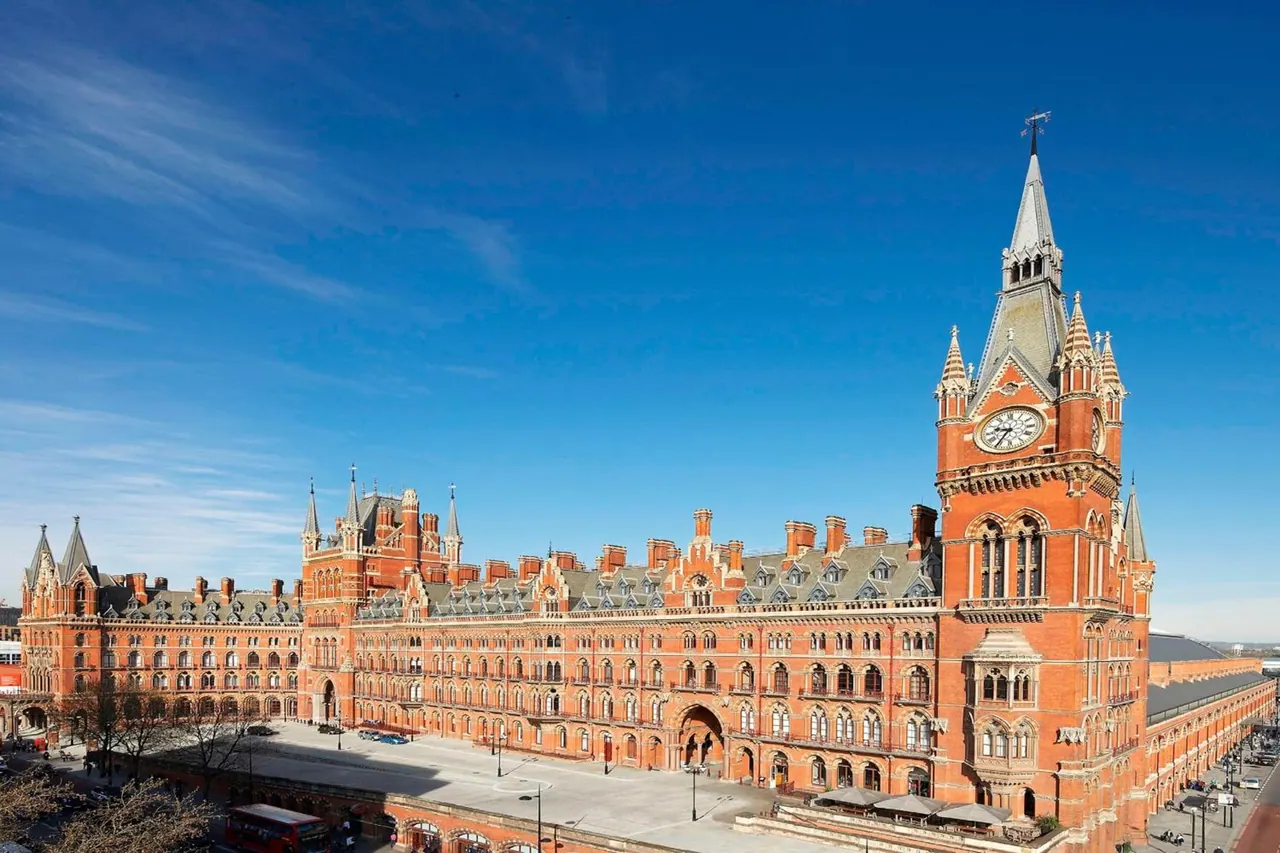 Exterior view of the red brick St Pancras Chambers building with its clock tower under a clear blue sky.