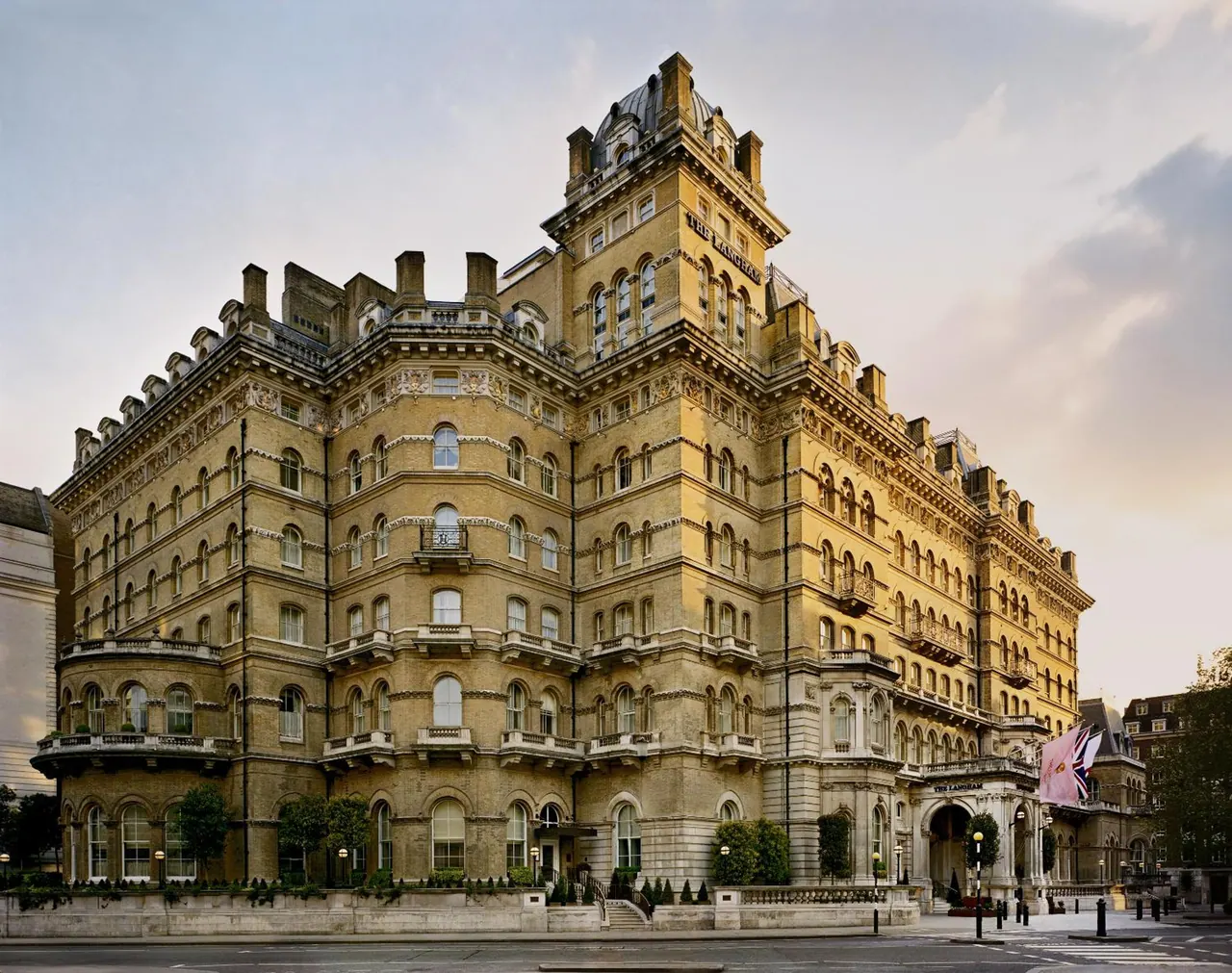 Exterior of The Langham hotel, a large stone Victorian building with a domed tower, viewed from the street corner.