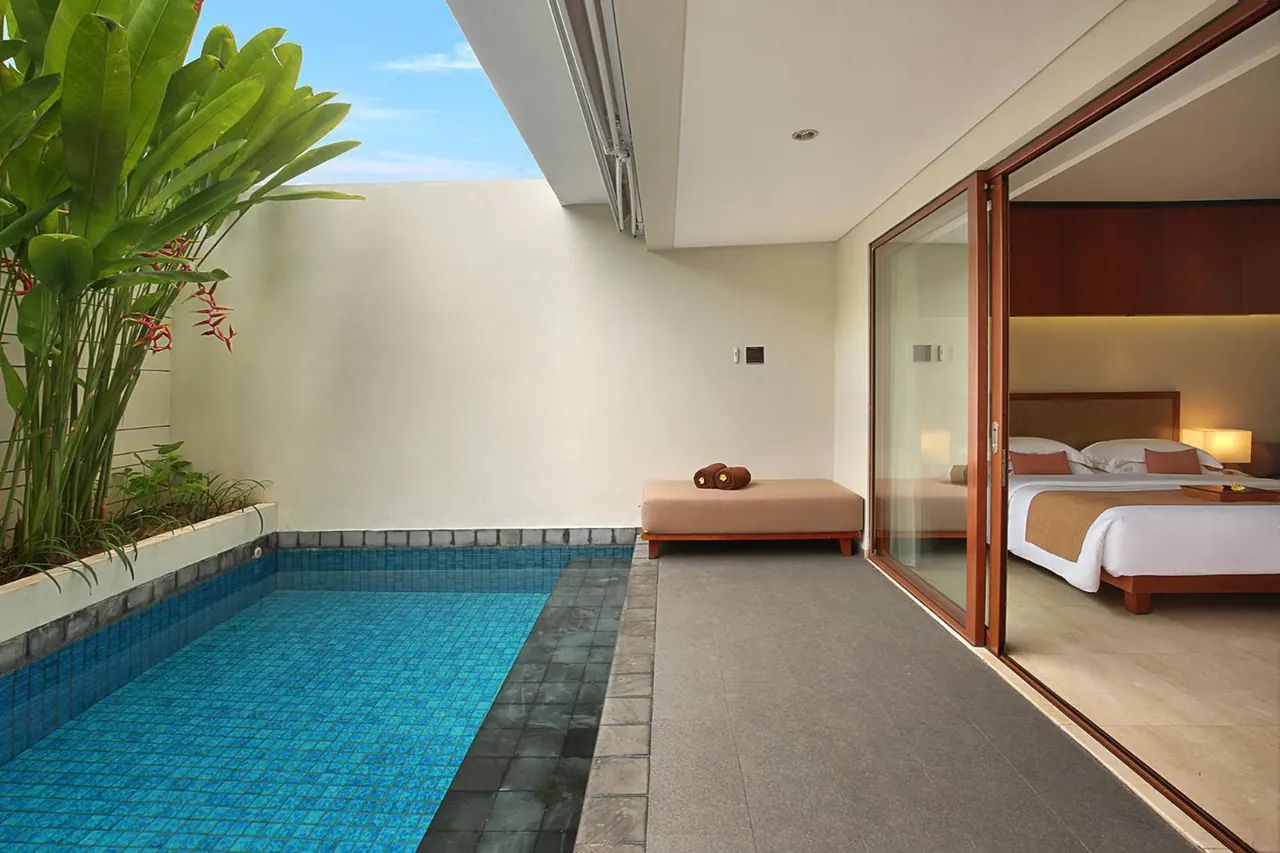 A small private pool sits on a walled terrace beside sliding glass doors that open onto a bedroom with a double bed.