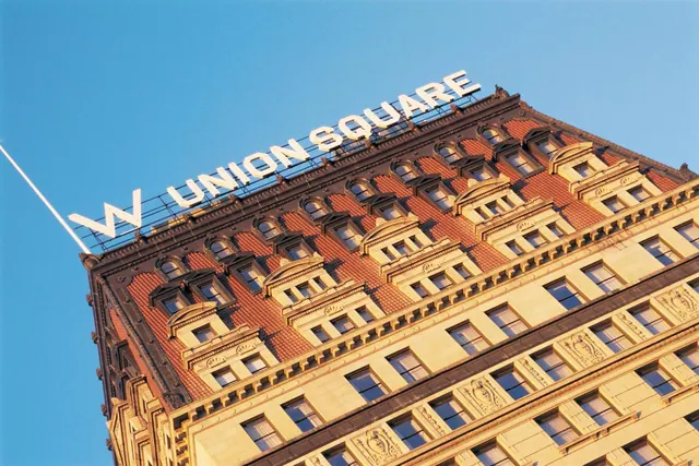A low-angle view of an ornate cream and terracotta building with a W Union Square sign on its roofline against a clear blue sky.
